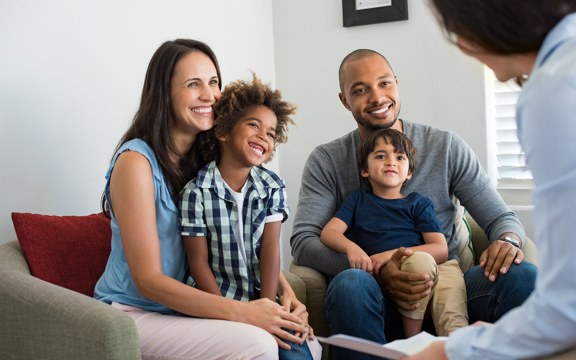 A smiling family of four sitting together on a couch